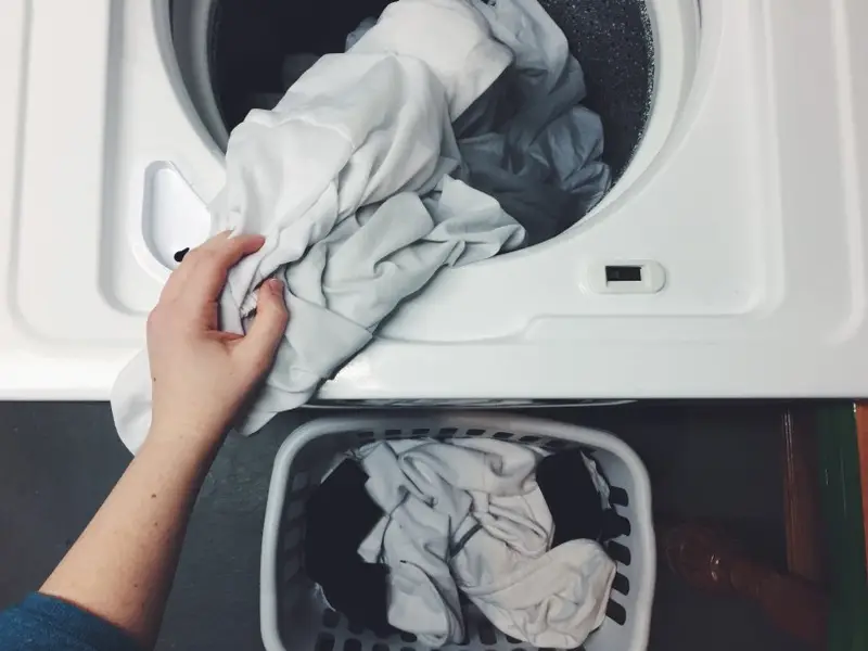 Clothes being loaded into a washing machine drum Ironing4U Hereford
